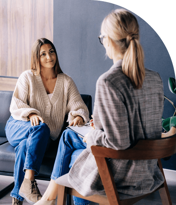 Two women having a conversation on chairs.